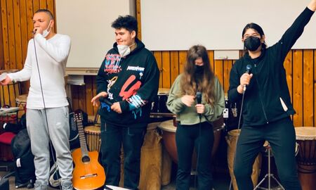 Vier Schüler*innen mit Mikrofon singen