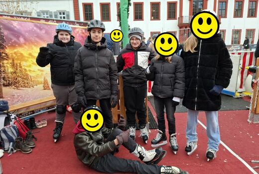 Sechs Sechsklässler posieren vor der Altstadtkulisse. Sie tragen Schlittschuhe.
