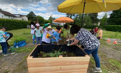 Kinder befüllen ein Hochbeet mit Grunschnitt
