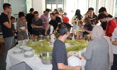 SchülerInnen und PädagogInnen stehen um das Buffet herum.