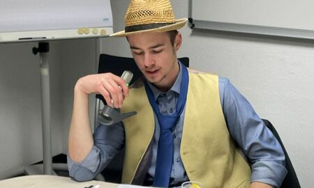 Ein Junge mit Hut und Krawatte spricht in ein Mikrofon