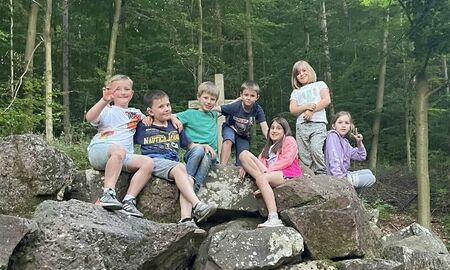 sieben Kinder sitzen auf einem Steinhaufen