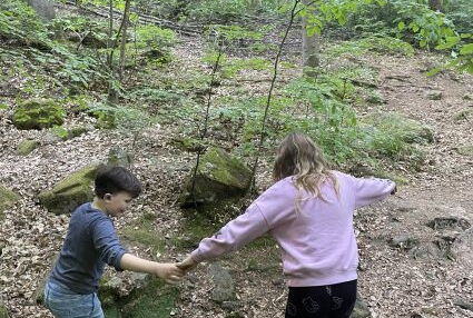Kinder testen eine Brücke über den Bach
