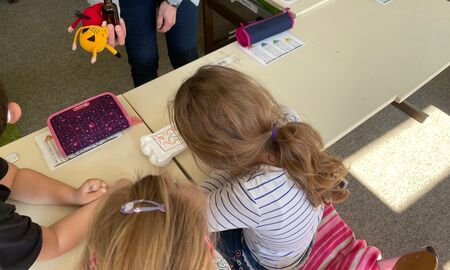 Zwei Schülerinnen betrachten einen mit Säure angegriffenen Styroporzahn und sehen die Wirkung von Karies.