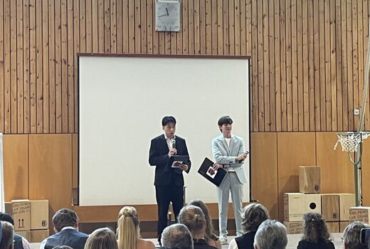 Zwei junge Männer stehen auf der Bühne und halten eine Rede.