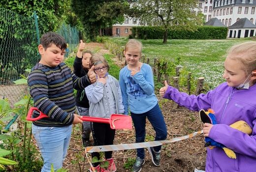 Fünf Schüler stehen um einen Komposthaufen und strecken den Daumen nach oben.