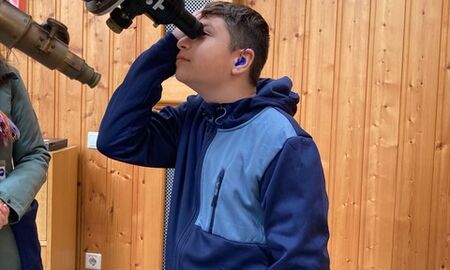 ein Kind schaut durch ein sehr großes Teleskop