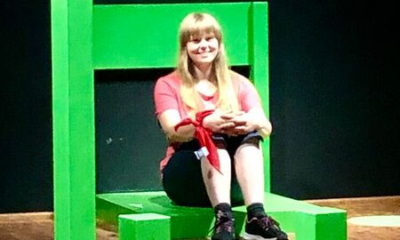 Ein grüner Riesenstuhl, auf dem eine Schülerin mit langen blonden Haaren sitzt.