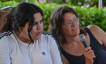 Eine Schülerin und eine Erzieherin singen in ein Mikrofon.