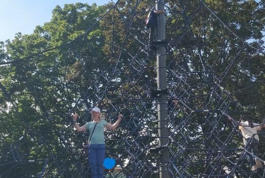 Kinder klettern auf dem Ketternetz. Ein Mädchen steht im Vordergrund.