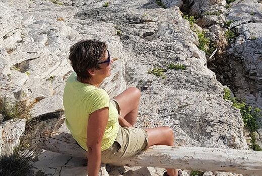 Andrea Göbel sitzt auf einem Baumstamm und schaut in die Ferne