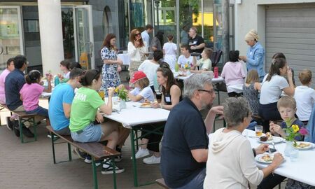 Viele Menschen sitzen auf Bierbänken und essen gemeinsam