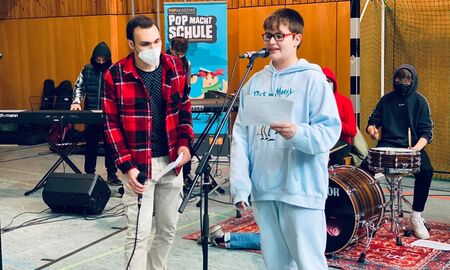 Im Vordergrund singen zwei Personen und hinten sieht man den Keyboardspieler und den Drummer