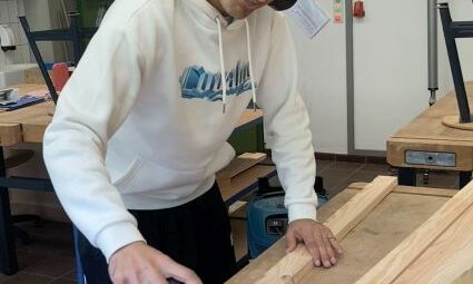 Ein junger Mann schleift ein Stück Holz