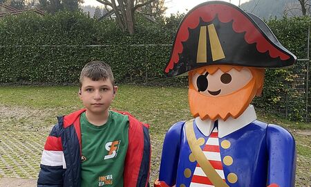 Ein Junge steht neben einer gleich großen Plastikfigur eines Piraten