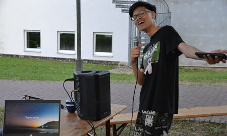 Ein Junge steht vor der Karaoke-Anlage und hat ein Mikrofon in der Hand.