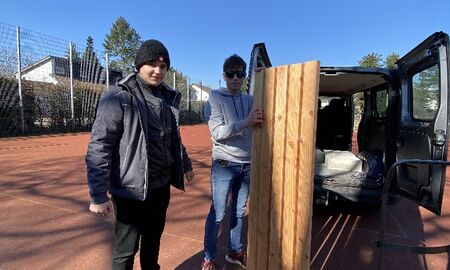 Zwei Schüler holen eine Sitzbank aus dem Kofferraum.