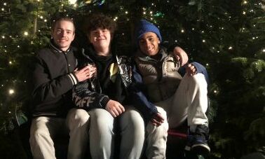 Drei Jungs sitzen vor einem Weihnachtsbaum