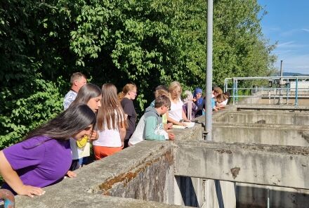 Eine Gruppe Kinder steht am Beckenrand. Manche schauen hinunter.