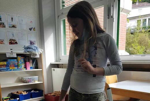 Schülerin zeigt mit dem Finger auf einen Hund der sie aufmerksam anschaut, Kind gibt Hund das Kommando Bleib