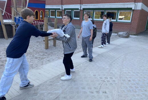 Eine Kette von Schülern, ein Sandsack wird weitergegeben