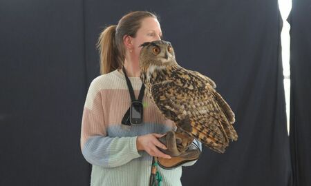 Eine Frau hält einen Uhu auf dem Arm