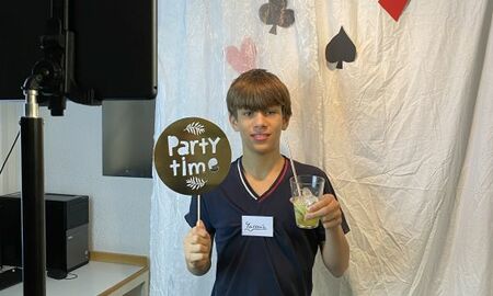 junger Mann vor einer Fotowand mit Cocktail