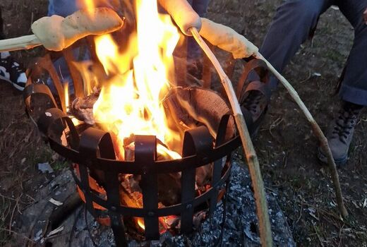 Stockbrot das über den Flammen des Feuerkorbs gegart wird