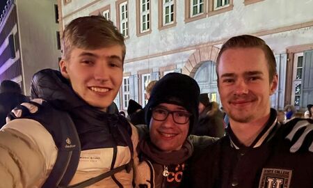 Drei Jugendliche trinken Kinderpunsch auf dem Weihnachtsmarkt