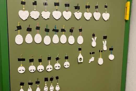 Ohrringe-Handarbeit an einer grünen Wand aufgehängt