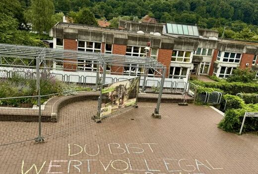 Auf dem Pausenhof steht in großen Buchstaben mit Kreise geschrieben: Du bist wertvoll, egal, was auf deinem Zeugnis steht.