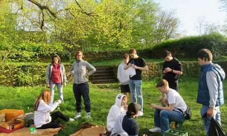 SchülerInnen und Erzieherinnen stehen bzw. sitzen auf der Wiese