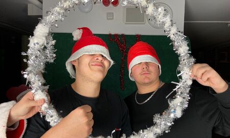 Zwei Schüler posieren für ein lustiges Foto. Sie haben Nikolausmützen auf schauen durch einen geschmückten Ring.