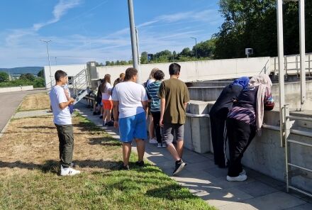 Schüler gehen entlang der Becken. Zwei lehnen am Beckenrand und schauen hinunter.