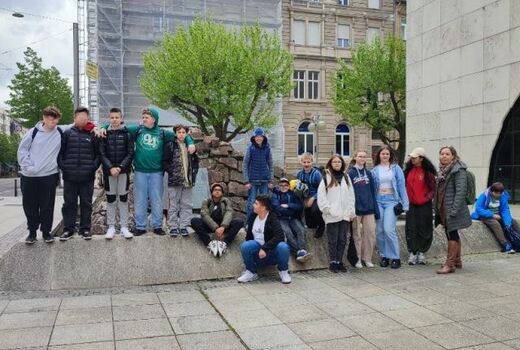 Die Gruppe, bestehend aus zwölf Schülern und einer Lehrerin, hat sich vor einem Brunnen zum Gruppenbild aufgestellt.