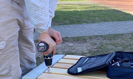 Ein junger Mann schraubt die Sitzfläche einer Bank fest