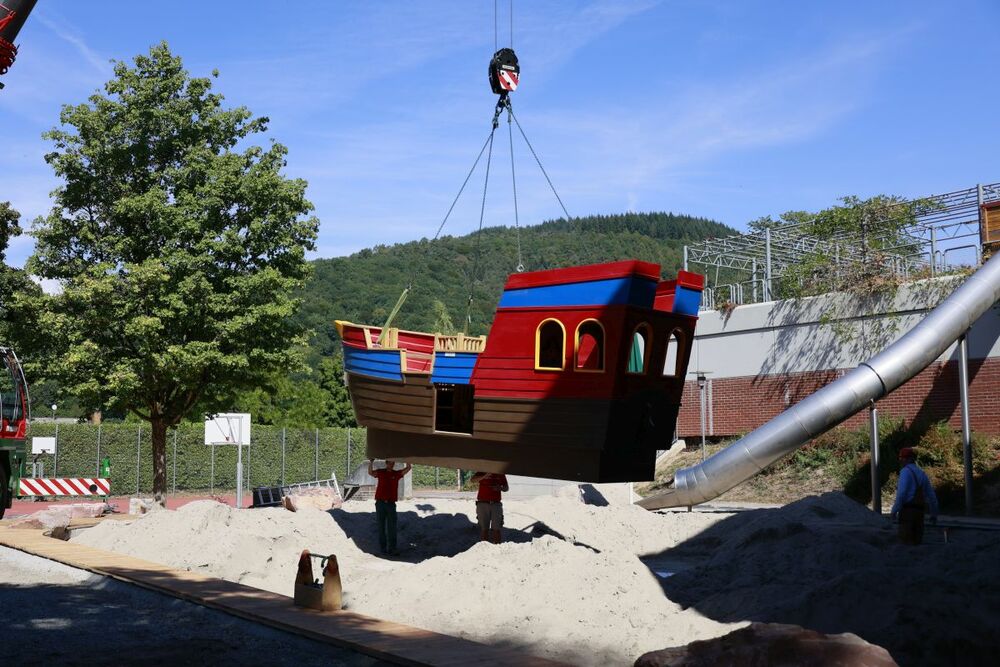 Zwei Handwerker und das Playmobil-Schiff auf dem Weg zum endgültigen Stellplatz.