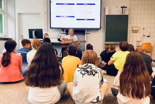 SchülerInnen und eine Lehrerin mit Gitarre singen