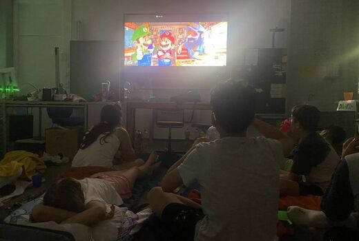 SchülerInnen sitzen und liegen auf dem Boden. Sie schauen einen Zeichentrickfilm.