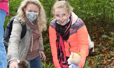Ein Mädchen hält Leo Löwenohr, eine Stoffpuppe, das Maskottchen vom Freitagsclub, in der Hand. Eine Lehrerin hält eine Maulwurfstoffpuppe in der Hand