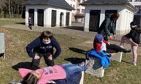 Zwei Bänke stehen im Gras. Auf jeder Bank liegt ein Kind