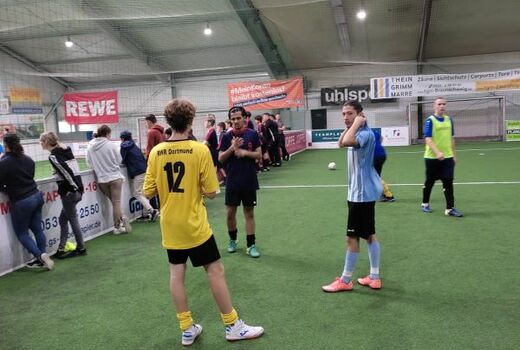 In der Fußballhalle. Drei Spieler stehen im Zentrum. Sie unterhalten sich.