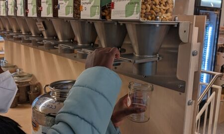 Kinderhände füllen Nüsse aus einem Vorratsbehältnis in ein Schraubglas