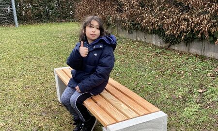 Ein Junge sitzt auf der Bank und streckt den Daumen in die Höhe
