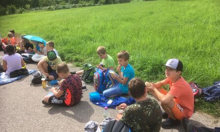 Schülerinnen und Schüler sitzen auf der Strasse und machen Pause, essen und trinken um sich zu stärken.