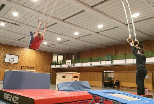 Zwei Personen schwingen an Ringen.