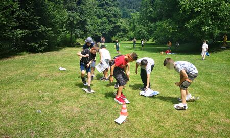 Schülerinnen und Schüler spielen ein Spiel auf einer großen Wiese, bei dem sie nur auf Zeitungen treten dürfen