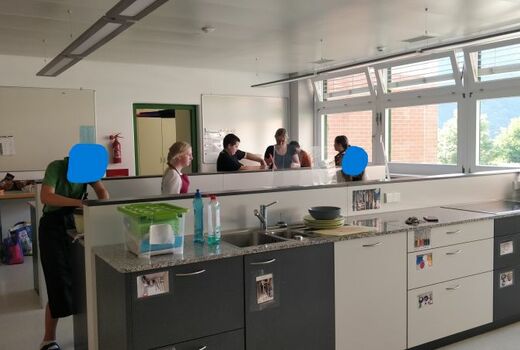 Sechs Schüler und eine Lehrerin werkeln in der Schulküche.