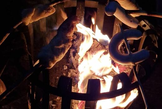 Stockbrot und Würste die über den Flammen des Feuerkorbs gegart werden