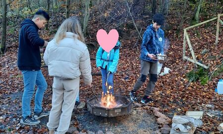 Schülerinnen und Schüler stehen um eine Feuerstelle herum